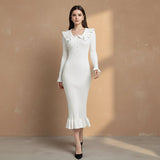 Woman wearing a white dress with ruffled details on a gray background