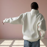 Person wearing a white sweater with a plain background