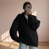 Person wearing a black oversized sweater taking a mirror selfie.