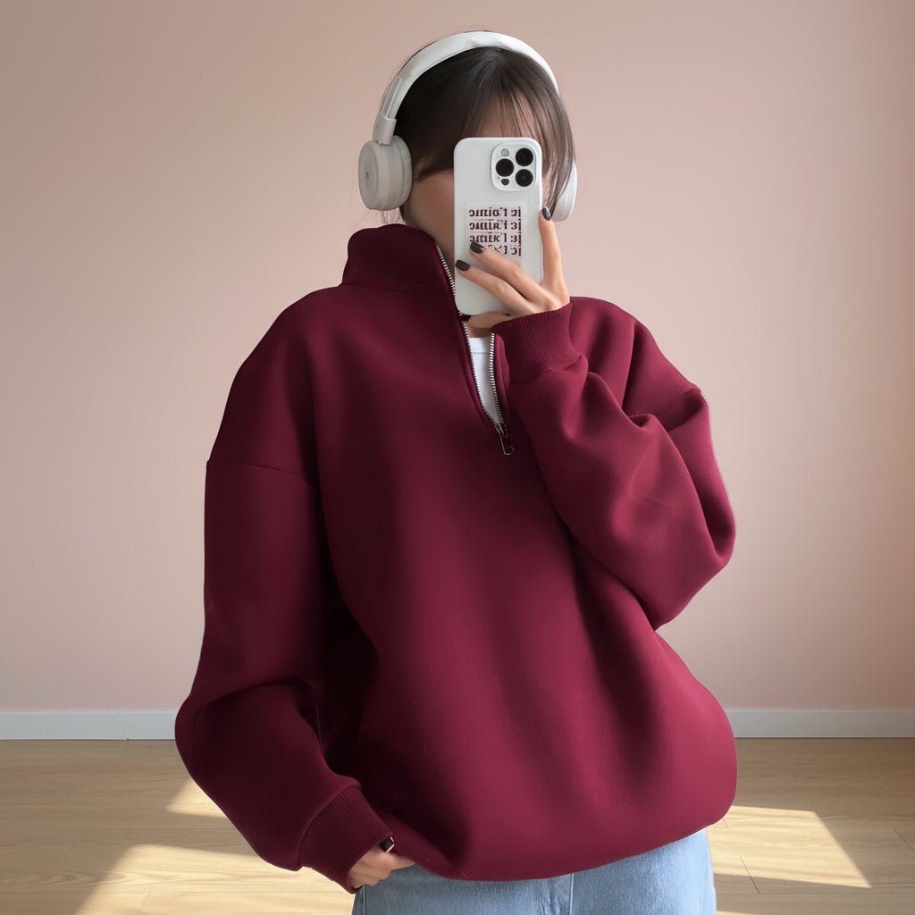 Person wearing a maroon hoodie and light blue jeans with a plain background