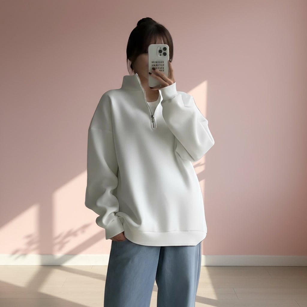 Person wearing a white sweater and light blue pants against a plain background